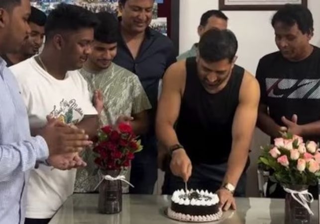 Dhoni in a sleeveless T-shirt beaming as he cut the cake